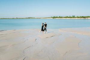 ungt par en kille med en flicka i svarta kläder går på den vita sanden