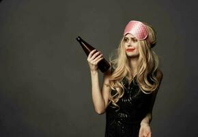 kvinna med en flaska av öl och en rosa sömn mask foto