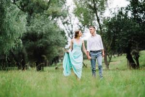 glad kille i en vit skjorta och en flicka i en turkos klänning går i skogsparken
