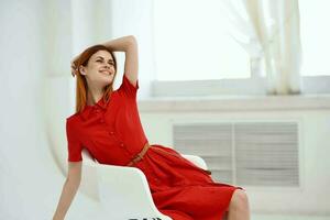 Söt kvinna i röd klänning Framställ på en stol lyx foto