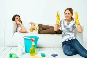 en man lögner på en soffa. en kvinna rengör upp hushåll rengöring foto