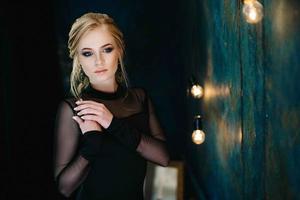 blond tjej med blå ögon i en svart klänning foto