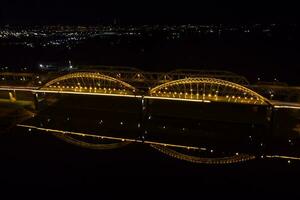 ljus lampor, broar med valv, natt stad. en väg bro tvärs över de flod, tagen från en Drönare. foto