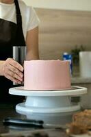 kvinna bakverk kock framställning choklad kaka med rosa grädde, närbild. kaka framställning bearbeta, selektiv fokus foto