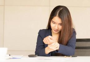 asiatisk affärskvinna som håller sin handledsmärta från att arbeta och använda datorn. kontorssyndrom