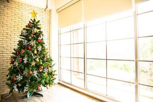 julgran dekorerad i vardagsrummet för att förbereda sig för det nya året. dekorera vardagsrummet och julgranen med en låda med röda bollar, gyllene bollar, gyllene klockor, snöstjärnor, strumpor. foto