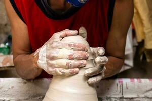 man framställning keramisk artiklar på de krukmakare hjul i en traditionell fabrik i de stad av raquira belägen i de avdelning av cundinamarca i colombia foto