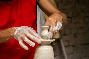 man framställning keramisk artiklar på de krukmakare hjul i en traditionell fabrik i de stad av raquira belägen i de avdelning av cundinamarca i colombia foto