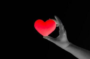 kvinna hand innehav tom röd hjärta på mörk bakgrund, symbol av kärlek eller dejting foto