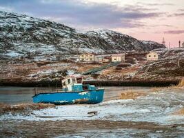 ett gammal rostig fiske båt övergiven förbi en storm på de Strand. kyrkogård av fartyg, gammal fiske by på de Strand av de barents hav, de kola halvö, teriberka foto