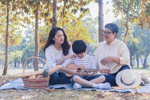 asiatisk familj tycker om att sitta i parken på höstlovet. foto