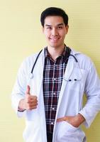 stående ung läkare på gul bakgrund foto