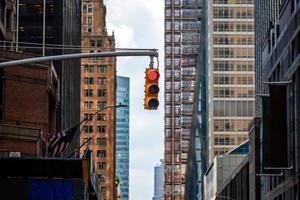 trafikljus med rött ljus ovanför manhatan gatan bland många skyskrapor foto