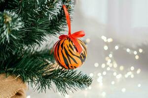jul boll målad som tiger Ränder på jul träd med en krans. 2022 är en år av de tiger. Lycklig ny år . symbol av år lunar kinesisk kalender tiger på jul boll. foto