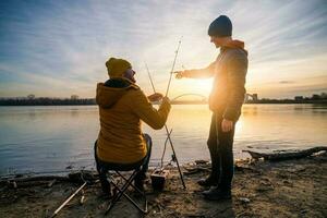 far och son är fiske på solig vinter- dag foto