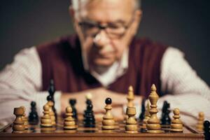 en senior man spelar schack foto