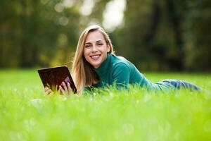 en kvinna utgifterna tid utomhus med en läsplatta enhet foto