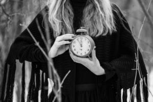 kvinna innehav en klocka på de skog. tid begrepp. foto