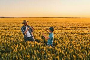 far och son stående i en vete fält foto