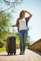 ung turist kvinna bärande en resväska foto
