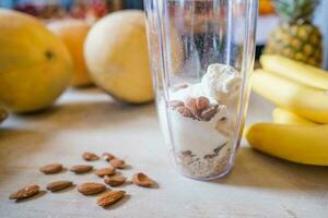 friska protein skaka på tabell med frukt och grönsaker Ingredienser runt om foto