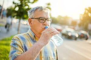 en senior man dricka vatten foto
