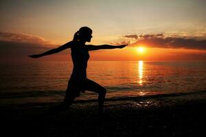 en kvinna på de strand håller på med yoga foto