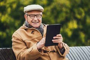 utomhus- porträtt av en senior man läsning från en läsplatta foto
