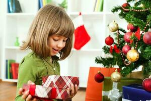 en ung flicka öppning en jul närvarande foto