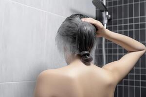 kvinna tvättning hår med schampo och dusch i de badrum. ai genererad foto