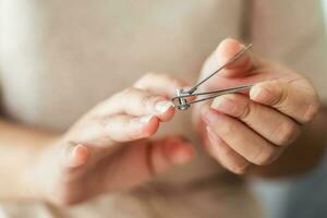 kvinna skärande fingernaglar använder sig av nagel klippare, sjukvård, skönhet begrepp. foto
