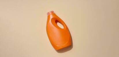 orange plast flaska för flytande tvättmedel, för tvättning kläder på en beige bakgrund, topp se foto
