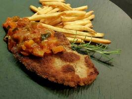 panerad wiener schnitzel med sida maträtter foto