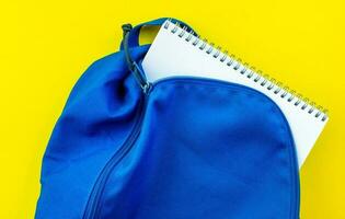 skola ryggsäck och anteckningsbok på en gul bakgrund. foto