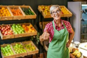 mogna kvinna Arbetar i frukt och grönsaker affär. porträtt av små företag mataffär ägare. foto