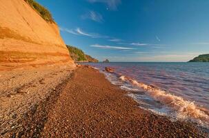 röd vågor på en röd sandsten strand foto