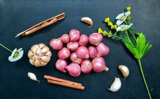 schalottenlök eller lök, vitlök och kanel som kök Ingredienser eller kryddor isolerat på en svart bakgrund. foto