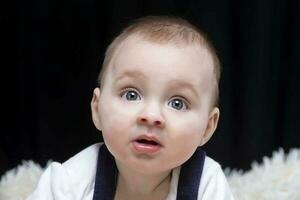 en skön unge utseende på de kamera i överraskning. bebis på fyra månader gammal. en rolig barn. foto