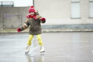 liten rolig pojke skridskoåkning på is i vinter. foto