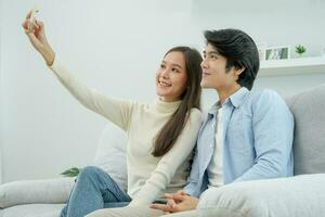 asiatisk par är njuter ny Hem och tar selfies tillsammans. Tonårs Make och fru efter äktenskap. lycka och ler och skratt i värma familj. gosa, värma kramar, tonåringar först kärlek foto