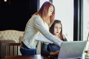 två asiatiska affärskvinnor som använder en bärbar dator