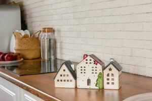 en modell av en hus på de bakgrund av kök möbel. de begrepp av uppköp en hus, verklig egendom inteckning, Hem interiör foto