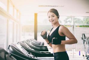 asiatiska kvinnor springer och joggar på löpbandet på gymmet foto