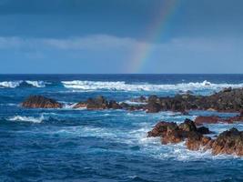 atlantiska vågor och en regnbåge vid den steniga stranden av Puerto de la Cruz Teneriffa kanarieöarna