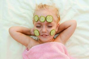 skön flicka med ansiktsbehandling mask av gurka. foto