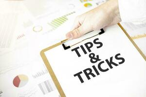 text tips och knep på vit papper tallrik i affärsman händer med finansiell diagram. företag begrepp foto