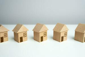 trä- leksak hus stå i en rad. hitta mest lämplig hus alternativ. erbjudanden på verklig egendom marknadsföra. inteckning. värdering av bostads- byggnader. fastighetsmäklare tjänster. uppköp och försäljning. foto