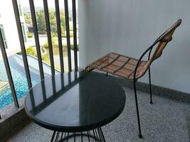 en runda svart tabell och brun korg- stol är på de terrass i de hotell för avslappning. där var solljus på de tabell i de morgon. foto