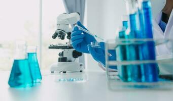 hand av forskare med testa rör och flaska i medicinsk kemi labb blå baner bakgrund foto
