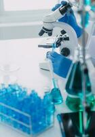 medicinsk eller vetenskaplig forskare forska och experimentera flerfärgad lösning, injektionsflaska och mikroskop i de laboratorium eller i de laboratorium förbi bär blå handskar och vit Kläder fullständigt. foto